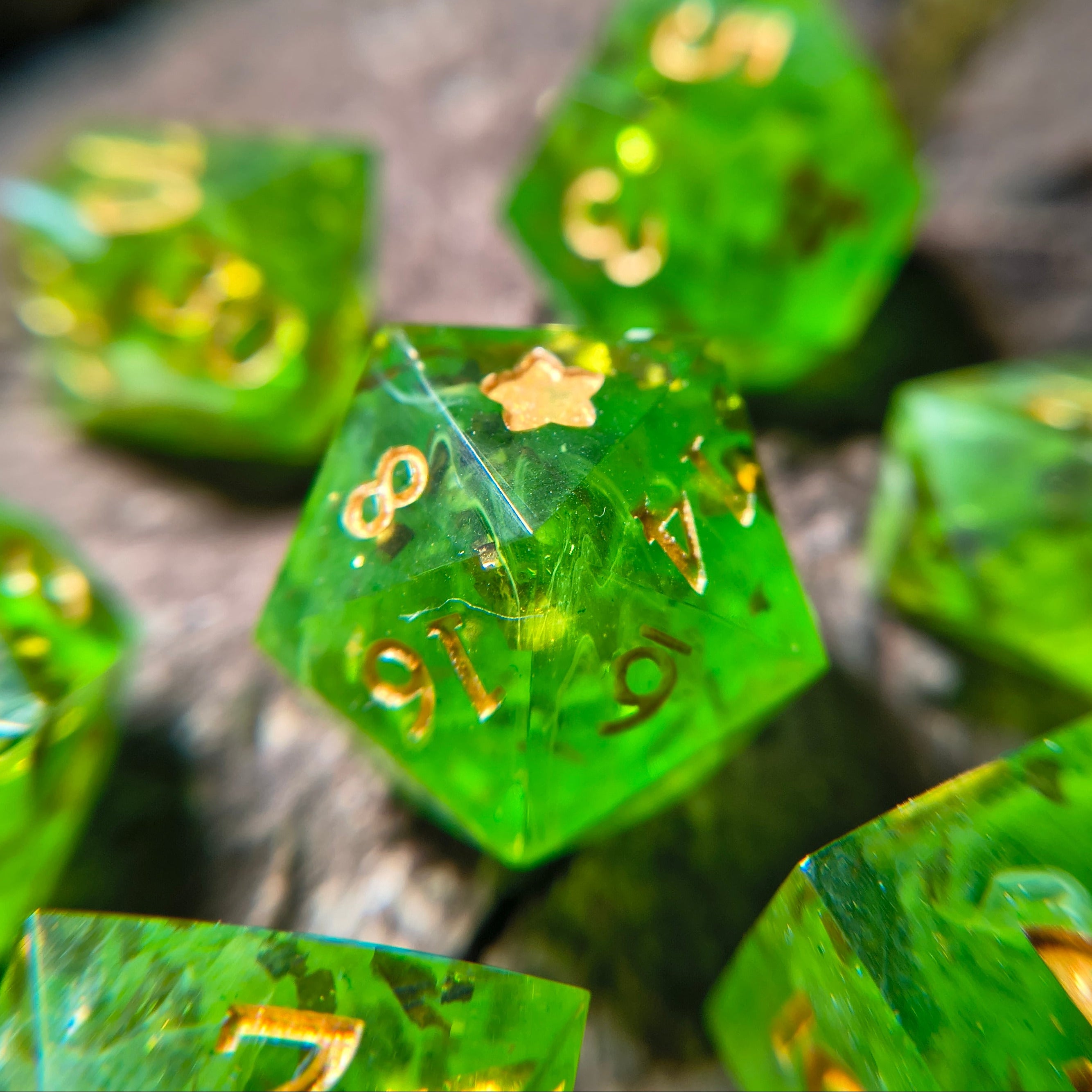 Close-up of green polyhedral dice with gold flakes and white swirls on a wood surface