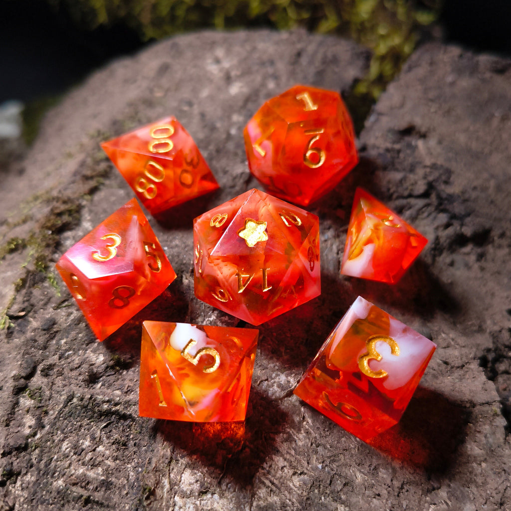 Set of orange polyhedral dice with white swirls on a wood surface