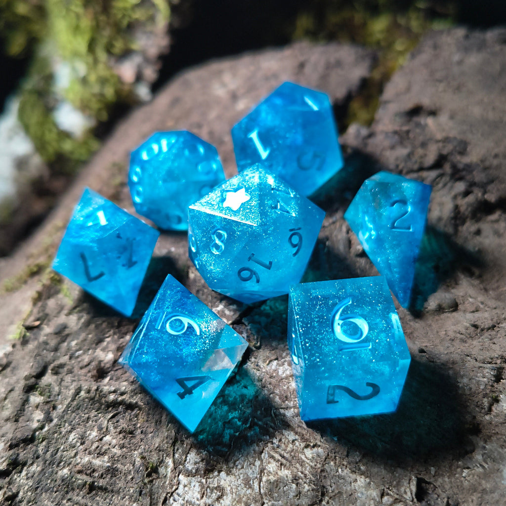 Set of sparkly blue polyhedral dice on a wood surface