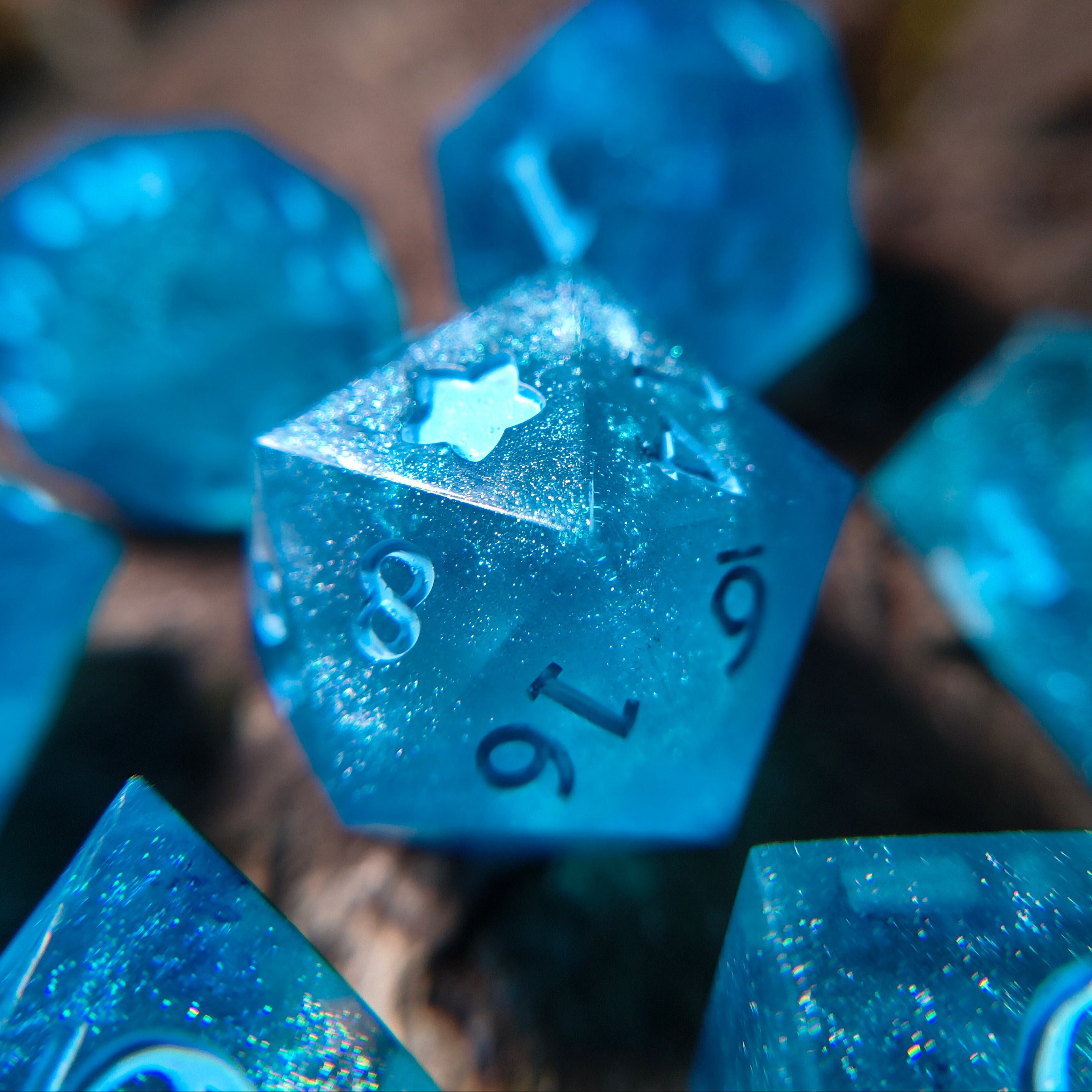 Close-up of sparkly blue polyhedral dice on a wood surface
