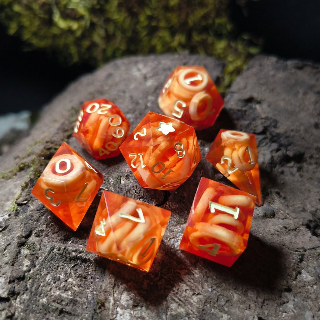 Set of red polyhedral dice with circular noodle colored inclusions on a wood surface