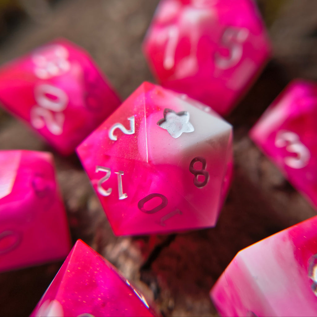 Close-up of pink polyhedral dice with white swirls on a wood surface
